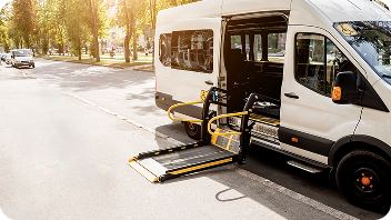 Wheelchair-accessible NEMT van with its ramp deployed at the curb